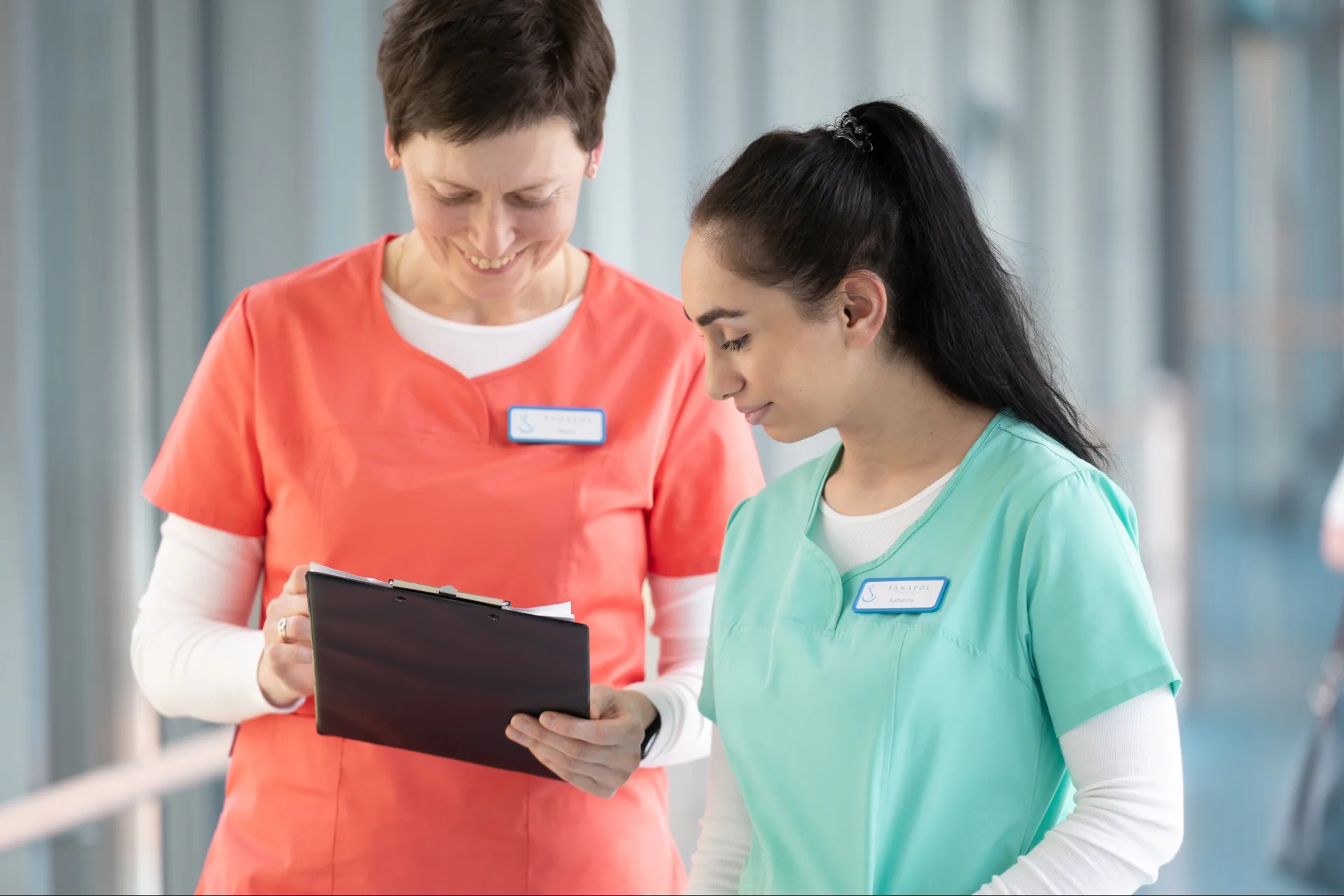 Zwei Pflegekräfte prüfen Informationen auf einem Klemmbrett